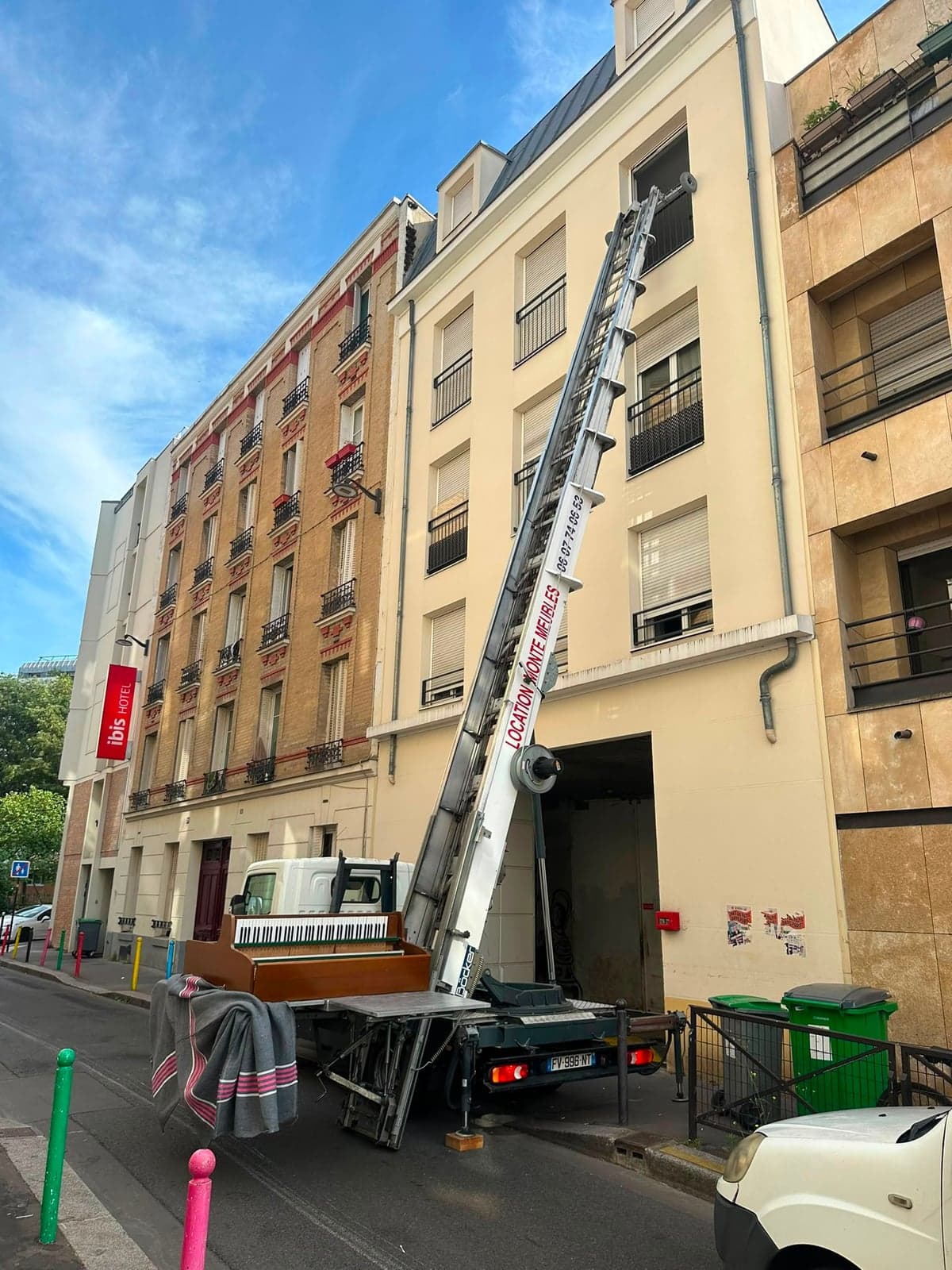 Piano droit sanglé sur le plateau du camion IDEV EXPRESS, monte-meuble déployé vers les étages d’un immeuble parisien