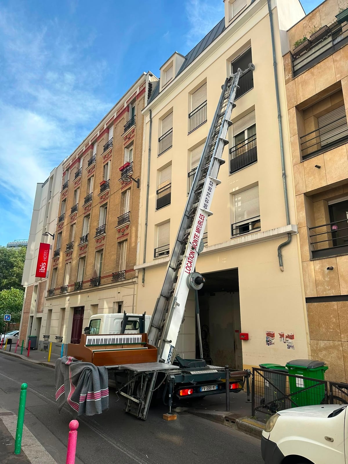 Piano droit sanglé sur le plateau du camion IDEV EXPRESS, monte-meuble déployé vers les étages d’un immeuble parisien